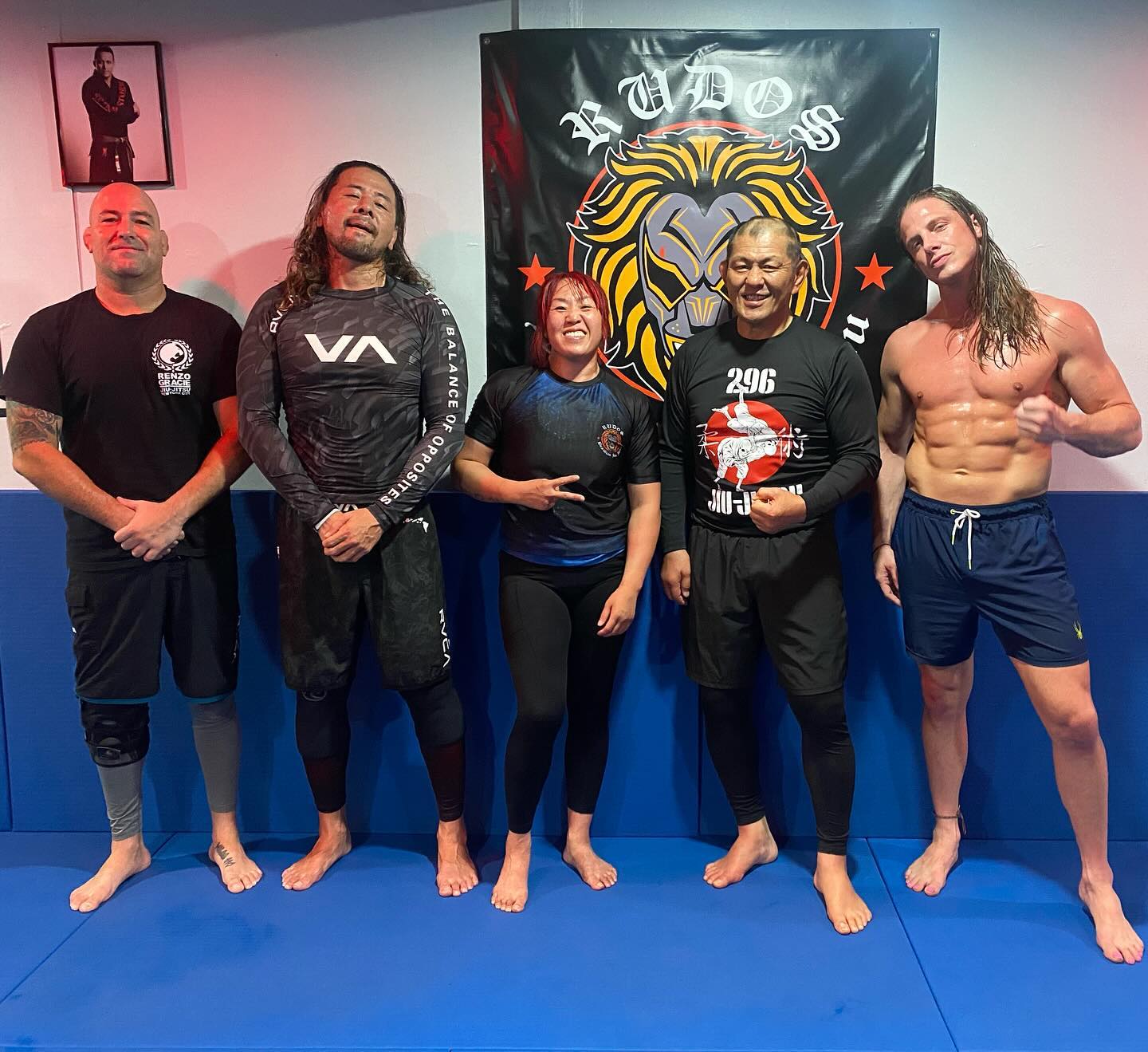 Professor David Floridia, Shinsuke Nakamura, Professor Karen Tran, Minoru Suzuki, and Professor Matt Riddle in front of the Rudos Lion crest banner